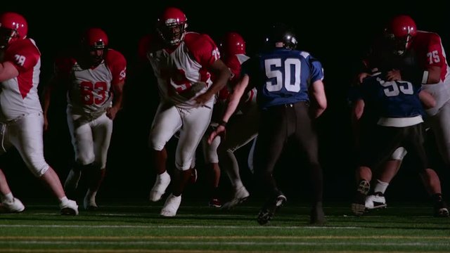 A football player takes the ball and runs through the line
