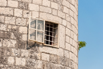 Window in stone tower with grille. Prison in fairy tale.
