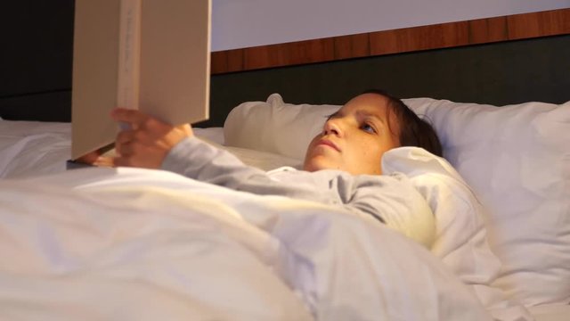 Woman reading her book in a comfortable bed at hotel room
