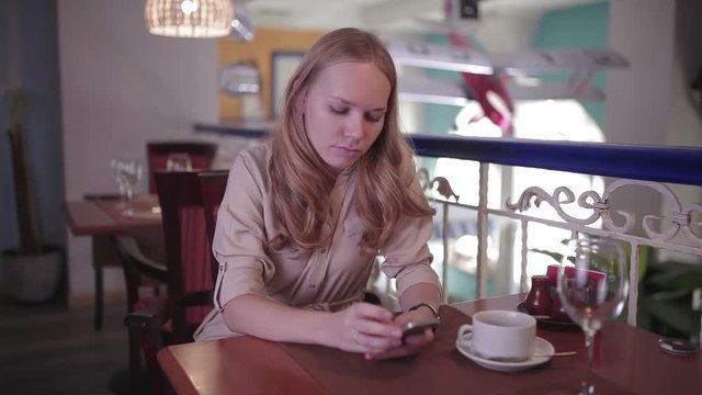 Woman is looking in the smartphone sitting in a restaurant