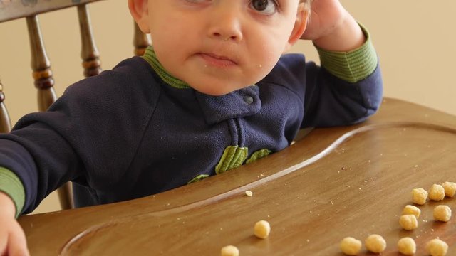Adorable baby boy eating cereal in his highchair