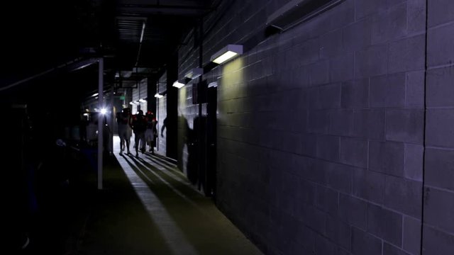A football team walks down a dark tunnel to the field before the start of a game