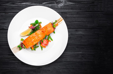 Salmon steak with salt, peppers, lemon, tomatoes on the black wo
