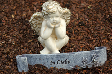 little angel sculpture decorate in small garden with a sign in front it - in love - in German