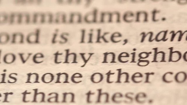 A closeup dolly shot of man reading bible love thy neighbor
