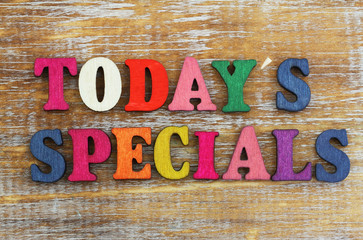 Today's specials written with colorful letters on rustic wooden surface
