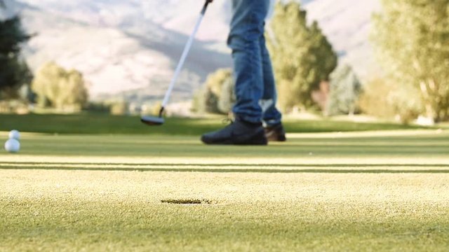 Slow motion of a person putting a golf ball on a golf course