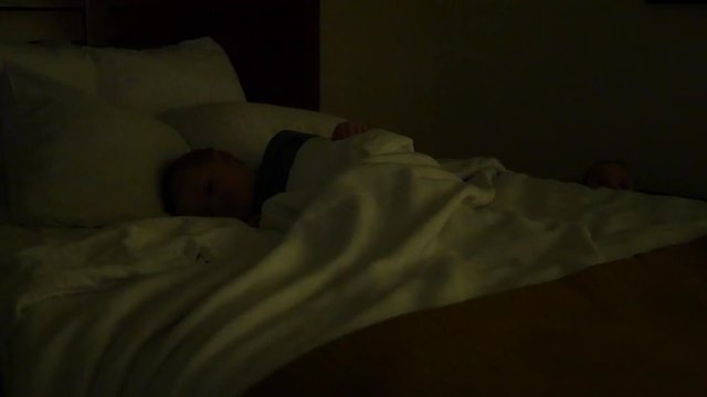 A little boy sleeping in a hotel bed at night dolly shot