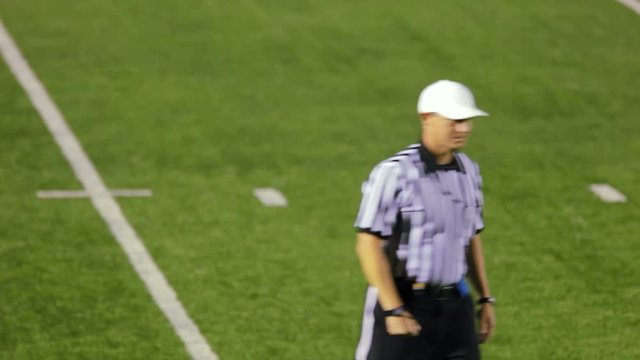 A football referee on the field makes a personal foul hand gesture