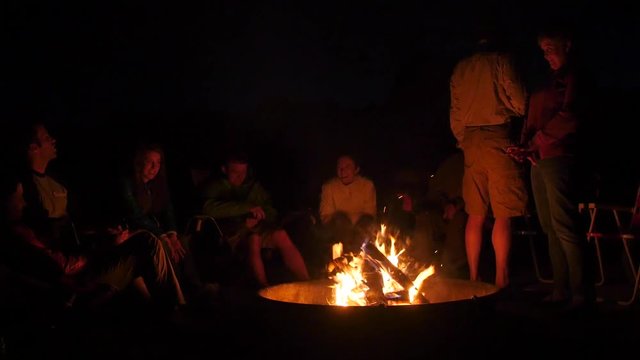 A family sitting around campfire burning at night