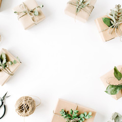 creative arrangement frame of craft boxes and green branches on white background. flat lay, top view