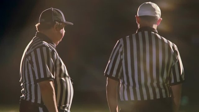 Football referees talk with each other on the field before the kick off