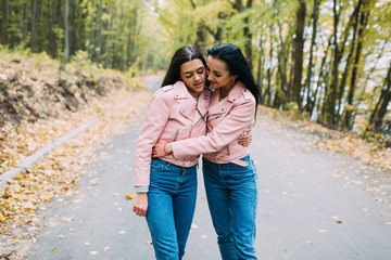 Two stylish, sexy and fashionable girls posing in autumn park