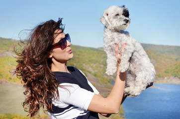 smiling woman hugging  her small havanese dog outdoor