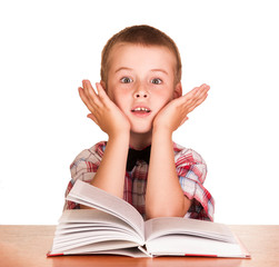 Cute surprised boy sitting at table on book, globe isolated.