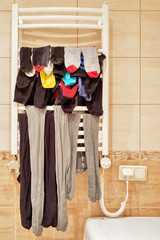 Lot of socks and leggings drying on bathroom radiator
