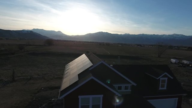 An aerial shot of house with solar and mountains at sunset with tree