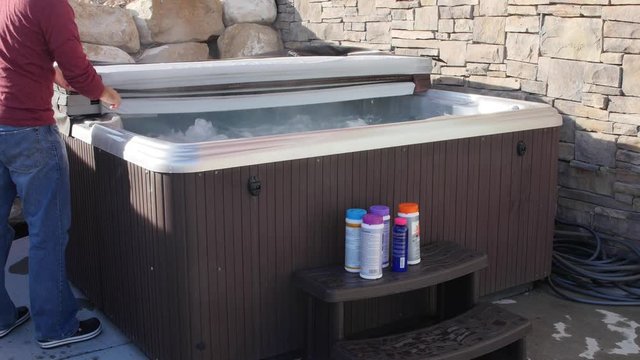 Man closes hot tub cover after putting in chemicals