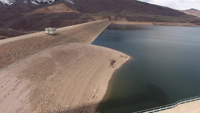 High aerial shot of low mountain reservoir and dam