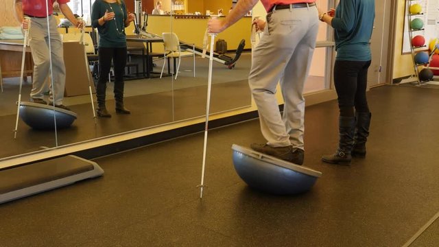A man practices balance in physical therapy dolly