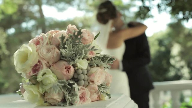 Bride's bouquet and kissing married couple on the background.