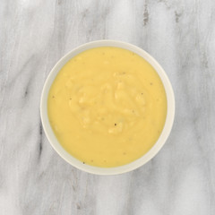 Cheddar potato soup in a bowl on a gray marble table top.