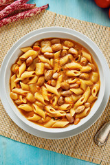 Pasta with beans in white dish on blue wooden table
