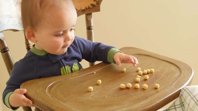 An adorable baby boy eating cereal in his highchair