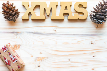 Christmas decoration with word xmas,pine cones and gift  on wooden background with copyspace, top view, flat lay.