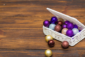 Christmas balls in white basket on brown wooden plate