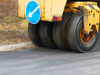 Road construction works with tyred road roller finishes asphalt