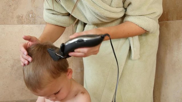 A dolly shot of mother cutting boys hair in shower