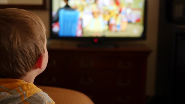 Little boy watches tv in hotel room dolly shot