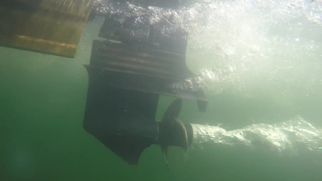 An underwater shot of a motor and propellar on a boat on a lake