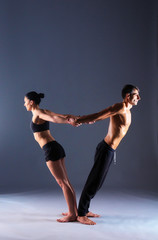 Fototapeta premium Young couple practicing acro yoga in studio together