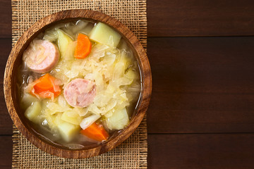Sauerkraut Eintopf mit Karotten, Kartoffeln und Würstchen, fotografiert mit natürlichem Licht...