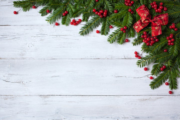 Naklejka na ściany i meble Christmas wooden background with branches of trees, berries and red ribbon