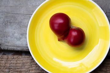 Ripe Tomato in Heart Shape on the Yellow Plate