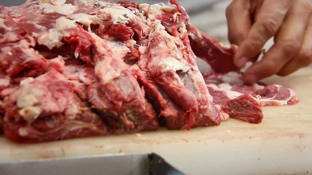 A close up of a butcher cutting meat in a Mexican market
