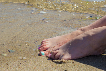 Woman feet with nail polish on sand