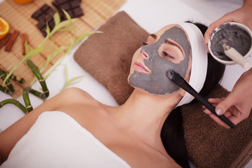 Spa massage for young woman with facial mask on face - indoors
