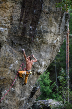 Young man climbing a rock with belay. Extreme rock climbing. Outdoor lifestyle. 