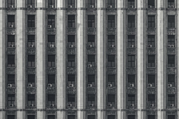 Architectural repetitive pattern with windows and air conditioner units in monochrome color tones.