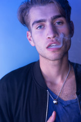 Obraz premium Portrait of young man smoking cigarette at club - selective focu