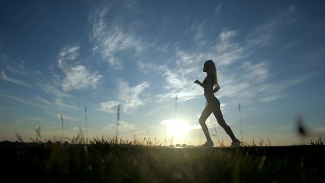 Running silhouette sexy girl on sunset