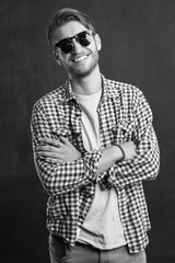 Trendy relaxed young man with a modern haircut standing against