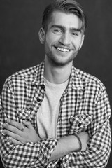 Happy young man standing with arms crossed over blackboard backg