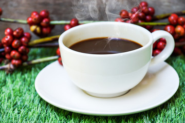 Coffee and raw coffee beans on artificial grass.