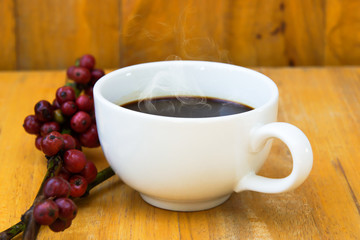 Hot coffee on the wood and raw coffee bean.