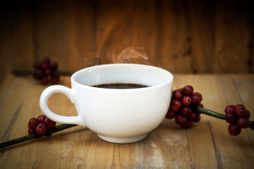 Hot coffee on the wood and raw coffee bean.
